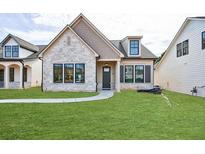 Charming single-Gathering home with stone facade, well-manicured lawn, and inviting entrance at 158 South Village Ave, Holly Springs, GA 30115