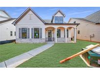 Charming home featuring a landscaped front yard, white siding, black trimmed windows, stone accents, and a welcoming front porch at 160 South Village Ave, Holly Springs, GA 30115