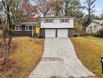 Split level home with brick and wood accents, featuring a yellow front door and a long driveway at 630 El Prado Ct, Stone Mountain, GA 30083