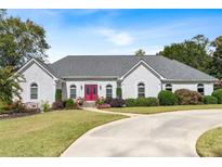 Charming one-story home with a gray roof, red front door, circular driveway, and landscaped front yard at 1453 Reagan Cir, Conyers, GA 30012