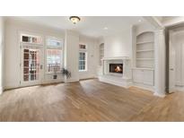 Bright living room with a fireplace, hardwood floors, and large windows leading to a small balcony at 77 Peachtree Ne Pl # 402, Atlanta, GA 30309