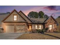 Charming brick home featuring a two-car garage and a neatly maintained front yard with mature landscaping at 1115 Harvest Brook Ne Way, Lawrenceville, GA 30043