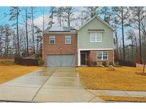 Two-story home with brick and green siding, a two-car garage, and a well-manicured front yard at 7272 Emma Ct, Douglasville, GA 30134