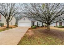Traditional home featuring a one-car garage and welcoming front porch, framed by mature trees at 2464 Hampshire Cv, Conyers, GA 30013