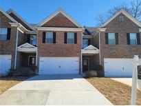 Charming brick townhome with attached garages, a manicured lawn, and a classic architectural design at 198 Britt Dr, Lawrenceville, GA 30046