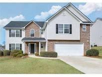 Charming two-story home featuring a mix of stone and vinyl siding, a two-car garage, and a well-manicured lawn at 3426 Bridle Brook Drive Ne Dr, Auburn, GA 30011