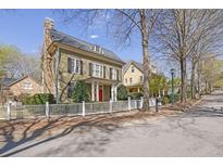 Charming two-story home with a stone chimney, red door, white picket fence, and well-manicured landscaping at 1421 Hedgewood Nw Ln, Kennesaw, GA 30152