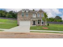 Charming two-story brick home featuring a two-car garage, well-maintained lawn, and classic architectural details at 1856 Kingsmere Run Dr, Loganville, GA 30052