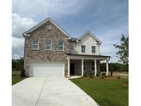 Charming two-story home featuring a classic brick facade, inviting front porch and attached two car garage at 1847 Kingsmere Run Dr, Loganville, GA 30052
