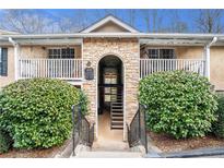 Condominium building featuring a stone archway entrance, upper balconies, and mature shrubbery at 3175 Seven Pines Ct # 207, Atlanta, GA 30339