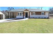 Charming renovated ranch-style home featuring white painted brick, a covered parking area and a well-manicured lawn at 900 King Rd, Jonesboro, GA 30236