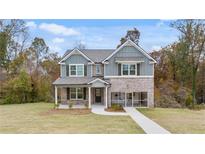 Beautiful two-story home with gray siding, brick accents, well-manicured lawn and cozy screened in porch at 1857 Kingsmere Run Dr, Loganville, GA 30052