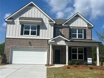 Charming two-story home featuring a brick and board-and-batten facade, black shutters, and a two-car garage at 1857 Kingsmere Run Dr, Loganville, GA 30052