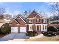 Beautiful brick home featuring a two-car garage and a well-manicured front yard on a sunny day at 4115 Oberon Se Dr, Smyrna, GA 30080