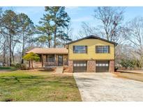 Charming split-level home with a brick and siding exterior, two-car garage and a spacious front yard at 7455 Dover Ct, Riverdale, GA 30274