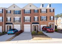Charming brick townhome with a well-manicured front yard and driveway with cars at 3782 Chattahoochee Summit Se Dr, Atlanta, GA 30339