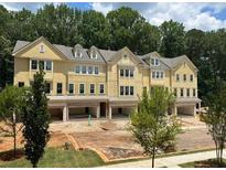 New construction townhomes featuring a yellow exterior, attached garages, and mature trees at 1983 American Way # 27, Kennesaw, GA 30144