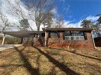 Front view of a brick home with a covered driveway, surrounded by lush trees and a long driveway at 2340 Dawn Dr, Decatur, GA 30032