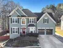 Charming two-story home featuring a well-maintained lawn, a red front door and a two-car garage at 3170 Wood Springs Sw Trce, Lilburn, GA 30047