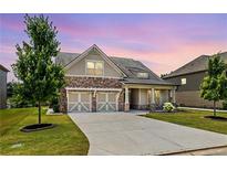 Charming exterior view of home featuring a stone and siding facade and a two-car garage at sunset at 145 Meadow Branch Ln, Dallas, GA 30157