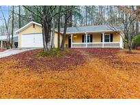 Charming yellow home with a welcoming front porch and well-maintained lawn covered with fallen leaves at 202 Journeys End, Peachtree City, GA 30269