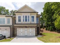 Beautiful two-story townhome boasts a brick facade, two-car garage, and manicured lawn at 1434 Casteel Lake Ln # 273, Buford, GA 30518