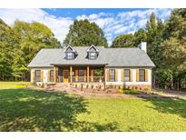 Charming home featuring a welcoming front porch, manicured lawn, and beautiful natural wood accents at 4392 Lower Fayetteville Rd, Sharpsburg, GA 30277