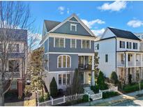Charming three-story home with a welcoming front porch, beautiful landscaping, and a white picket fence at 203 Hubbard Rd, Woodstock, GA 30188