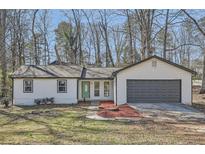 Charming single-story home with a gray garage door and a well-maintained front yard at 1669 Glen Arm Dr, Lithonia, GA 30058
