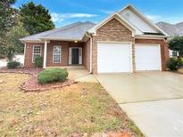 Charming brick home featuring a two-car garage and stone facade detail at 221 Long Dr, Mcdonough, GA 30253