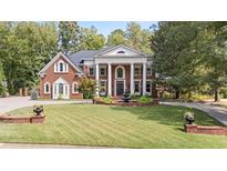 Stately brick home featuring manicured lawn, circular drive, and elegant water fountain at 9275 Chandler Blf, Alpharetta, GA 30022