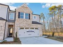 Charming two-story townhome boasts a brick facade, two-car garage and professionally landscaped yard at 552 Pennsy Aly, Mableton, GA 30126