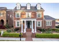 Stunning two-story brick home with a manicured lawn, dormer windows, and lion statues at the entrance at 8095 Georgetown Cir, Suwanee, GA 30024