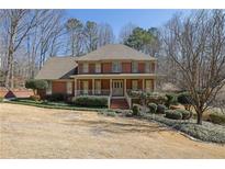Charming brick home featuring a welcoming front porch, manicured lawn and mature landscaping at 3290 Spain Rd, Snellville, GA 30039