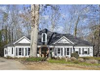 Charming white home with black shutters, arched entryway, beautiful landscaping, and inviting curb appeal at 6170 Wellington Ct, Cumming, GA 30040