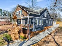 Two-story home featuring a welcoming elevated front porch with wooden stairs and blue painted wood with cedar shake accents at 1985 Lois Pl, Atlanta, GA 30318
