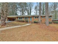 Charming brick ranch-style home with blue shutters and covered carport in a wooded setting at 2941 Pine Valley Cir, East Point, GA 30344