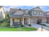 Charming two-story home featuring a stone and brick facade, covered porch, and well-manicured landscaping at 3220 Celebration Blvd, Suwanee, GA 30024