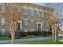 Charming brick townhome featuring a wrought iron fence and well manicured front lawn at 2111 Lilly Nw Way, Atlanta, GA 30318