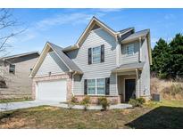 Charming two-story home with light gray siding, black shutters, attached garage and well-kept lawn at 325 Nutwood Trce, Locust Grove, GA 30248