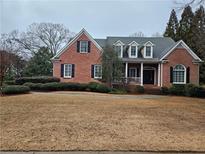 Charming brick home featuring dormer windows, a covered porch, and manicured landscaping at 3894 Stone Lake Nw Dr, Kennesaw, GA 30152