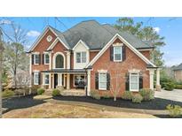Beautiful two-story brick home featuring a manicured front yard and covered front porch entry at 720 Weybridge Pl, Alpharetta, GA 30022