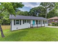 Charming home featuring a well-maintained lawn, complemented by a light blue front door and black shutters at 6977 Eunice Dr, Riverdale, GA 30274