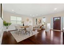 Open-concept dining room featuring hardwood floors, neutral walls, a large window, and modern decor at 250 High Court Way, Locust Grove, GA 30248