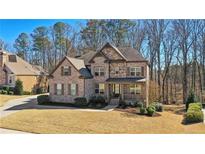 Charming two-story home featuring a brick and stone facade, manicured lawn, and mature trees adding to its curb appeal at 4520 Valence Dr, Cumming, GA 30040