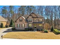 Charming two-story brick and stone home with manicured front lawn and inviting covered front porch at 4520 Valence Dr, Cumming, GA 30040