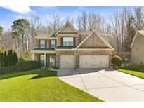 Charming brick two-story home featuring a two-car garage, manicured lawn, and mature trees at 149 Manor Lane, Woodstock, GA 30188