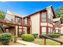 Inviting two-story condo with beige siding, red trim, a balcony, and lush landscaping at 904 Wentworth Ct, Alpharetta, GA 30022