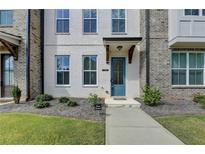 Charming townhome with a blue front door and painted white brick facade with a manicured lawn at 4320 Sims Park Overlook, Suwanee, GA 30024