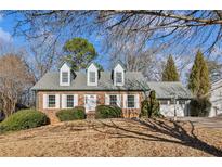 Charming brick home featuring dormer windows, a well-manicured lawn, and a two-car garage at 5352 Waterford Dr, Dunwoody, GA 30338